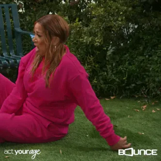 Tired+Work+Out+GIF+by+Bounce.gif A woman in a pink sweatsuit does situps in a backyard and falls back onto the grass, with the text 'act your age' and the Bounce network logo on screen.