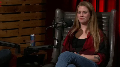 oct29-rooster-teeth.gif A woman with long red hair in a plaid jacket sits in a podcast chair and smiles quietly.