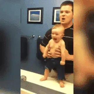 2bfa8d86-ff57-f311-9eea-b11b28142beb.gif A man holds a baby upright by the arms, walking the baby's feet along a ledge.