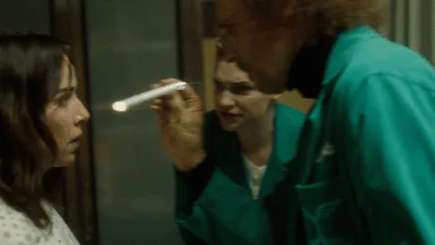 31699489-85b1-51ea-b016-6f30dc5e9ecb.gif A curly-haired man in a teal jacket points a small flashlight at a woman's eye during an exam.