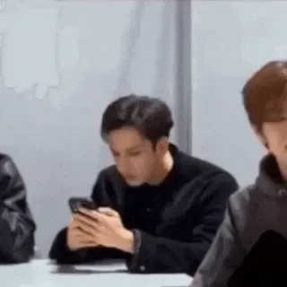 Confused+Phone+GIF.gif A young man in a black sweater looks at his phone at a table beside another person.