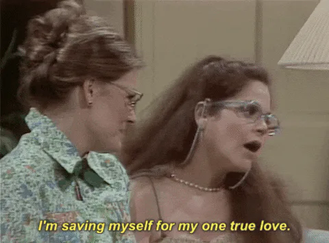 Two women say 'I'm saving myself for my one true love' in a retro living room.