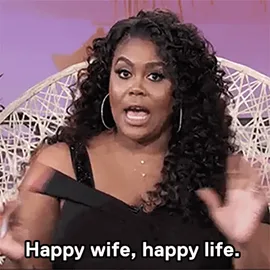f987466c-84c4-6606-3cc4-f969d6eab2db.gif A woman with curly hair gestures while saying 'Happy wife, happy life.'