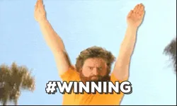 winning+GIF.gif A bearded man in an orange shirt jumps with arms raised under palm trees, captioned '#Winning.'