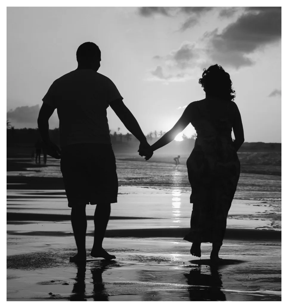 Image-14.png Silhouette of a couple holding hands while walking on a beach at sunset.