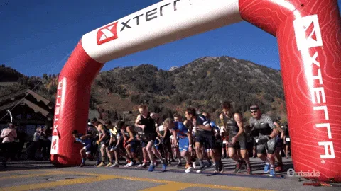 Lets+Go+Running+GIF+by+Outside+TV.gif Runners burst forward at a start line under a red inflatable arch reading XTERRA.