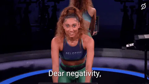 A fitness instructor points while saying 'Dear negativity, close the door on your way out.'
